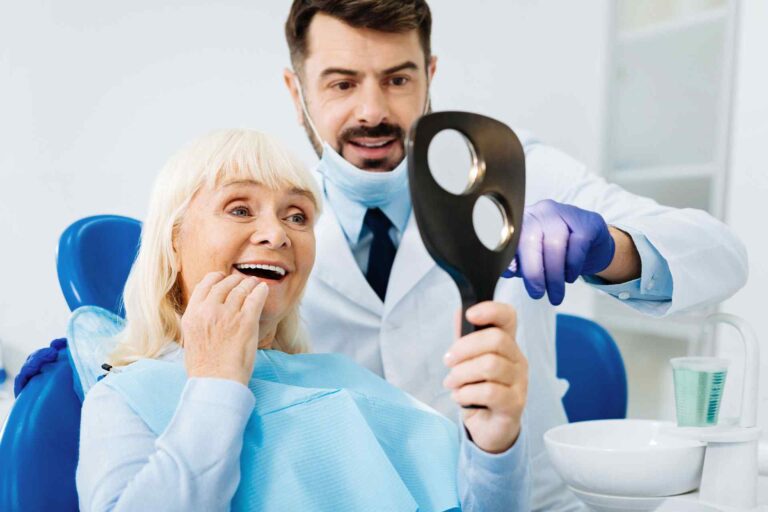 A dentist showing an elderly woman how to brush her teeth.