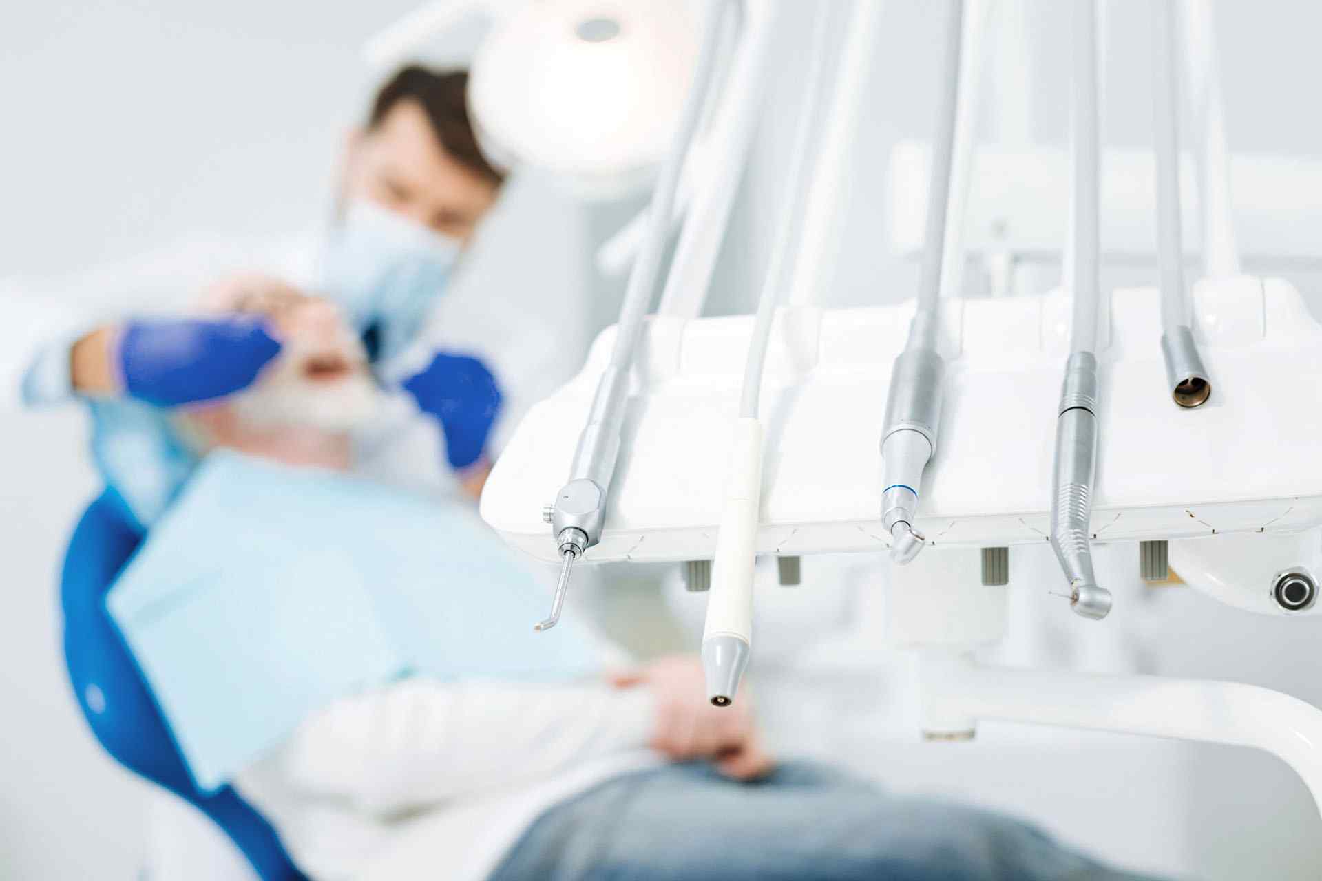 A dentist is sitting in front of the patient.
