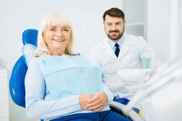 A woman sitting in a chair with a dentist behind her.